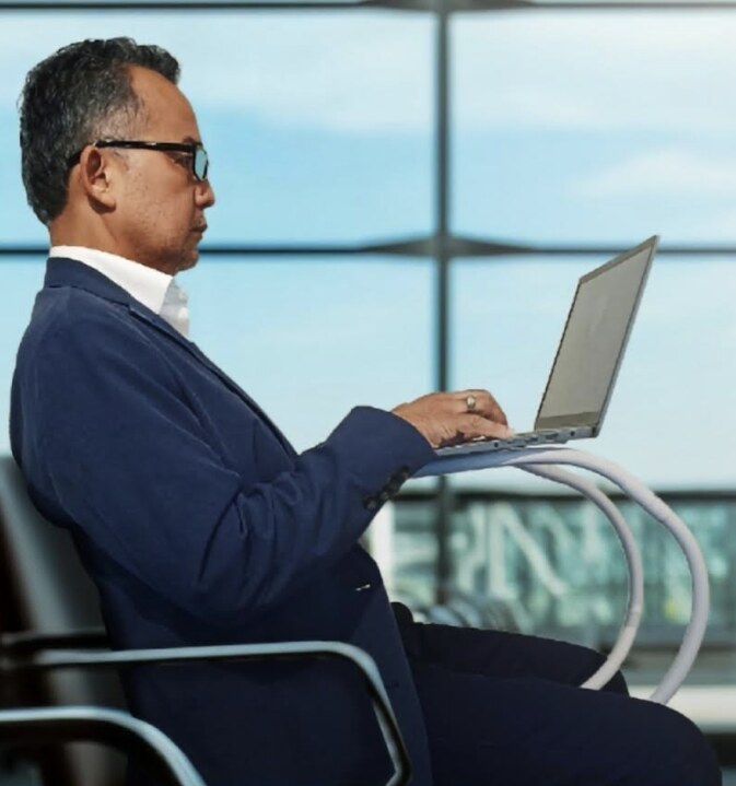 A business traveler typing on a laptop supported by Prod-UP-tivity in an airport lounge